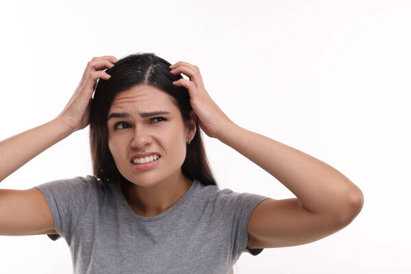 Эмоциональная женщина исследует свои волосы и кожу головы на белом фоне. Проблема перхоти