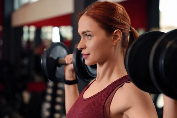 Athletic young woman with barbell training in gym, space for text