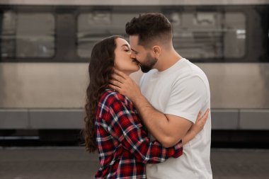 Uzun mesafeli ilişki. Tren istasyonunda öpüşen güzel bir çift.