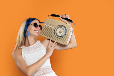 Turuncu arka planda retro radyo alıcısı olan mutlu hippi kadın. Metin için boşluk