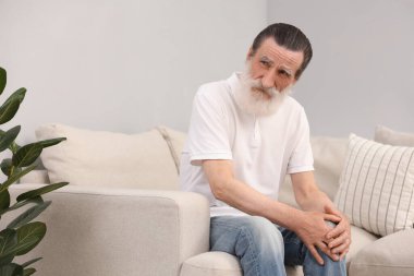 Evdeki kanepede diz ağrısı çeken son sınıf öğrencisi. Romatizma belirtileri