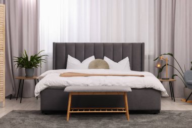 Şık bir yatak odası. Büyük yatak odası, kanepe, lamba ve çiçek.