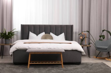 Şık bir yatak odası. Büyük yatak odası, kanepe, lamba ve çiçek.