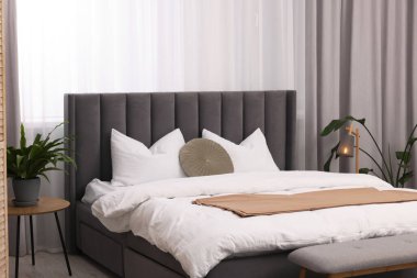 Şık bir yatak odası. Büyük yatak odası, kanepe, lamba ve çiçek.