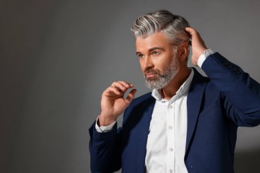 Koyu gri arka planda güzel saç stili olan kendine güvenen bir adamın portresi. Metin için boşluk