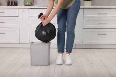Mutfaktaki çöp kutusundan çöp torbası çıkaran kadın, yakın plan.