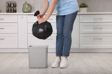 Mutfaktaki çöp kutusundan çöp torbası çıkaran kadın, yakın plan.