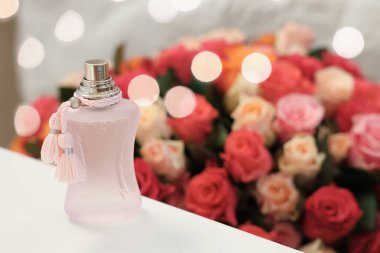 Beyaz masadaki bir şişe parfüme karşı güzel güller. Metin için boşluk