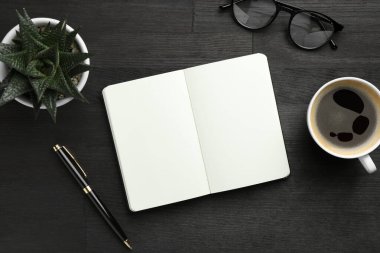 Düz kompozisyon, açık defter ve siyah ahşap masa üzerine kahve. Metin için boşluk