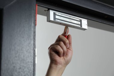 Tornavidalı bir adam elektromanyetik kapı kilidi yerleştiriyor, yakın plan. Ev güvenliği