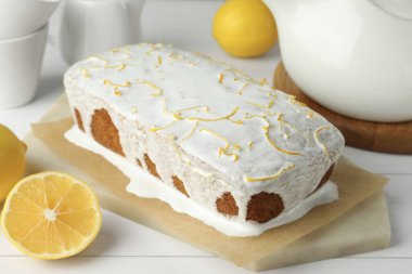 Lezzetli limonlu kek ve beyaz ahşap masada turunçgil meyvesi, yakın plan.