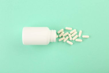 Turkuaz arka planda şişe ve vitamin kapsülleri, üst görünüm