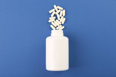 Mavi arka planda şişe ve vitamin kapsülleri, üst görünüm