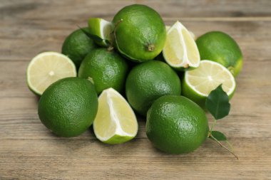 Tahta masanın üzerinde taze limon ve yapraklar yığını, yakın plan.