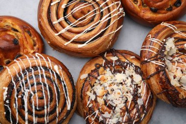 Açık gri masada farklı leziz dürümler, düz yatış. Tatlı çörekler.