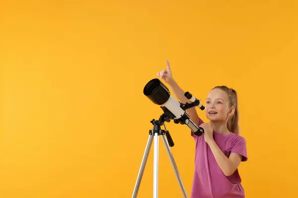 Menina Animada Com Telescópio Apontando Para Algo Fundo Laranja Espaço — Fotografia de Stock