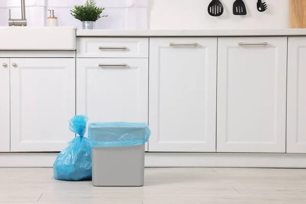 Plastic garbage bag and trash can in kitchen, space for text
