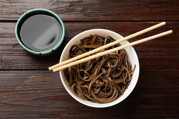 Lezzetli karabuğday erişteleri (soba), yemek çubukları ve ahşap masa üzerindeki sos, düz yatak