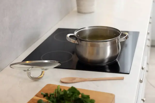 Pot with tasty soup on cooktop in kitchen