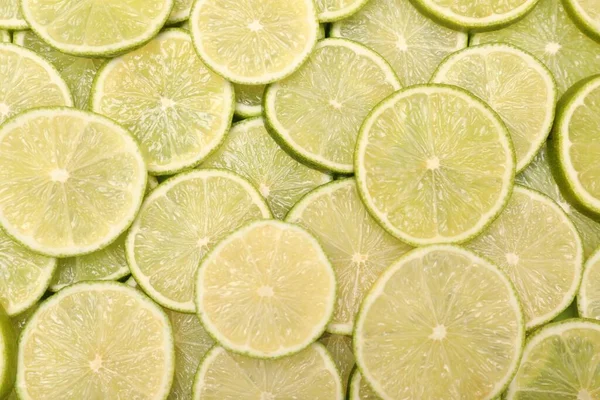 Many juicy lime slices as background, top view