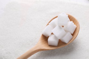 Arka plan olarak beyaz şeker ve kaşığın farklı türleri, görünümün üzerinde. Metin için boşluk