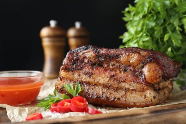 Ahşap tahtada soslu ve kırmızı biberli fırında domuz göbeği servis ediliyor.