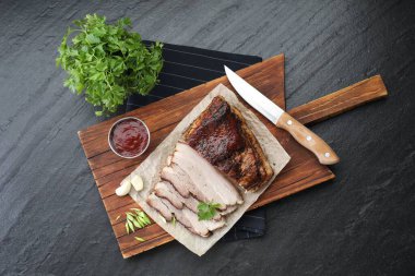 Soslu fırında domuz göbeği ve siyah desenli masanda maydanoz.