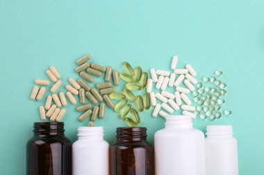 Turkuaz arka planda şişeler ve farklı vitamin kapsülleri, düz yatış
