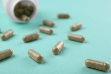 Turkuaz arka planda şişe ve vitamin kapsülleri, yakın plan