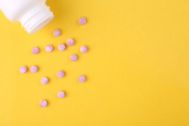 Sarı arka planda şişe ve vitamin hapları, üst manzara. Metin için boşluk