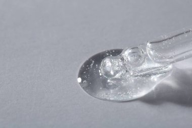 Işıklı arka planda kozmetik serumu olan bir boru, makro görünüm. Metin için boşluk