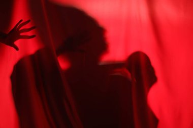 Kırmızı kumaşın arkasında kafatası olan ürkütücü bir hayalet silueti.