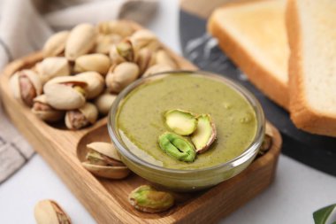 Beyaz masada servis edilen fıstıklı krema ve fındıklar.