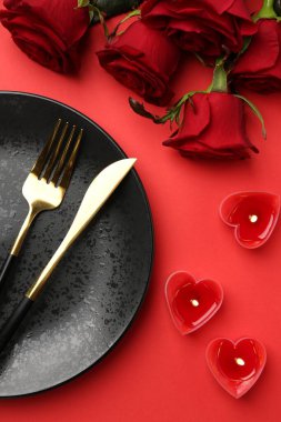 Kalp şeklinde mumlarla döşenmiş bir yer ve kırmızı masa üzerinde bir buket gül, düz. Romantik yemek.