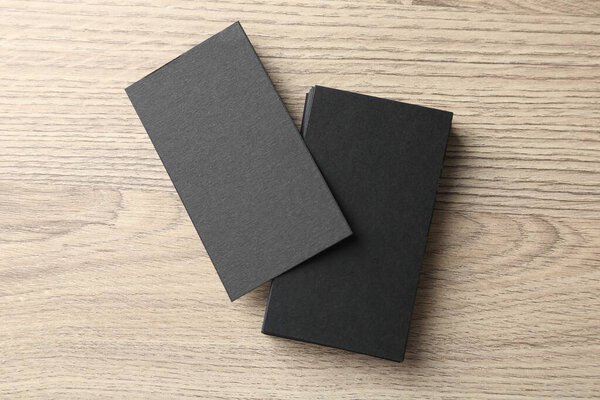 Черные визитки на деревянном столе, вид сверху. Макет для дизайна