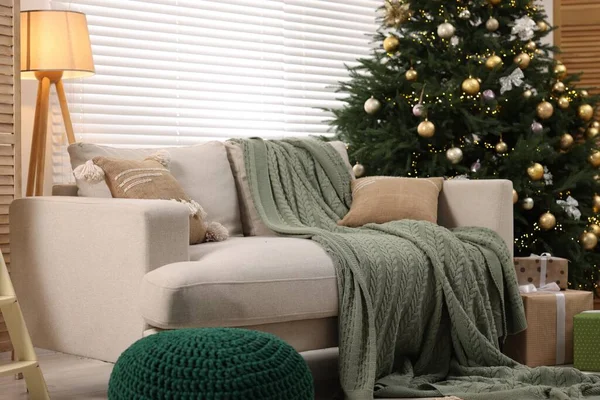Sofa near Christmas tree in room. Festive interior design