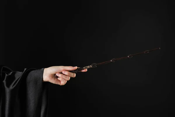Wizard holding magic wand on black background, closeup