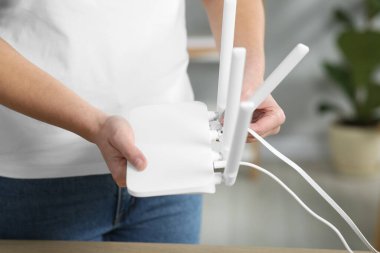 Kabloyu Wi-Fi yönlendiricisine bağlayan kadın.