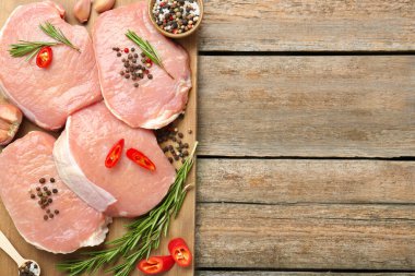 Ahşap masada çiğ domuz eti ve baharat parçaları, üst manzara. Metin için boşluk