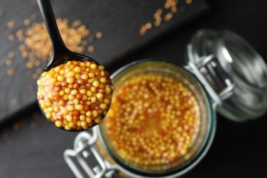 Kavanozun üzerine hardal dökülmüş kaşık, yakın plan.