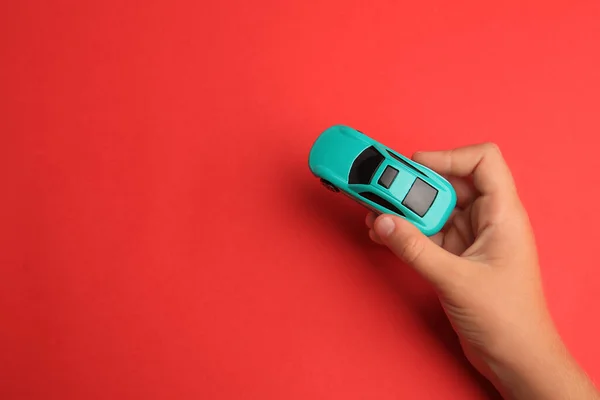 Child holding toy car on red background, top view. Space for text