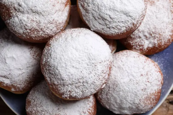 Delicious sweet buns with powdered sugar on plate, top view