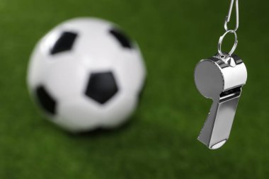 Futbol hakem ekipmanı. Metal düdük ve futbol topu yeşil çimlerin üzerinde, metin için yeri olan yakın plan