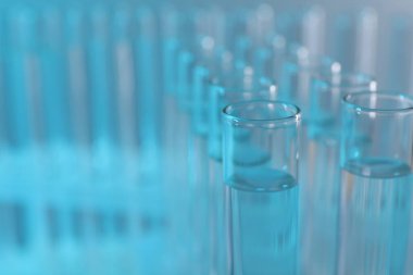 Laboratuvar analizi. Açık mavi arkaplanda birçok cam test tüpü, metin için yakın çekim ve boşluk