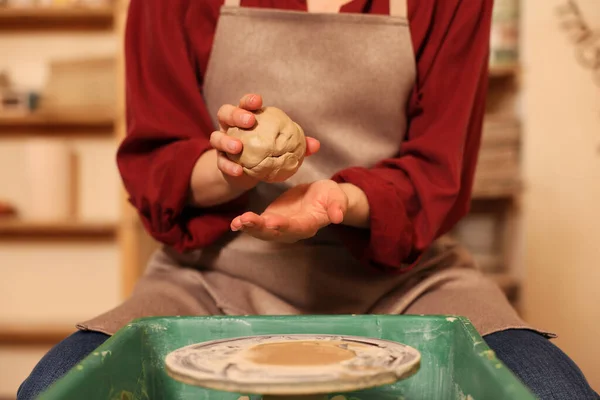 Woman crafting with clay over potter\'s wheel indoors, closeup