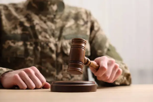 Law concept. Man in military uniform with gavel at table, closeup. Space for text