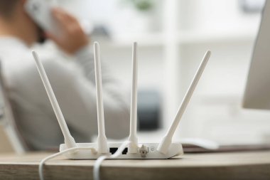 Ahşap masada çalışırken akıllı telefondan konuşan adam, Wi-Fi yönlendiricisine odaklan.
