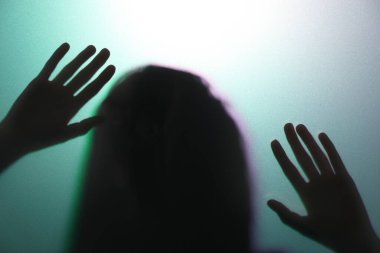 Camın arkasındaki tüyler ürpertici hayalet silueti renk arkaplanına karşı