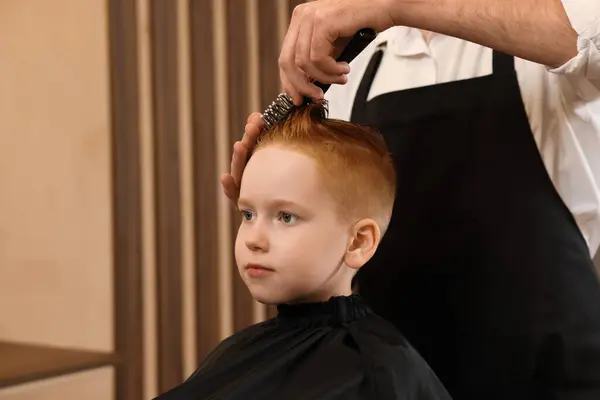美容室で男の子の髪をブラッシングするプロの美容師 — ストック写真