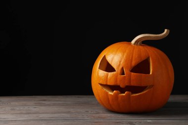 Ahşap masa üzerinde balkabağından yapılmış korkunç Jack O 'Lantern siyah arka planda, mesaj için yer var. Geleneksel Cadılar Bayramı dekorasyonu